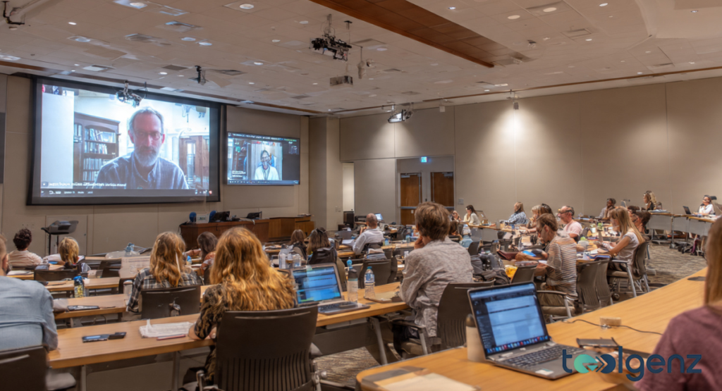 A professional student attending a remote lecture via a high-definition video interface. The screen shows complex data analytics, representing the university's online master's programs.